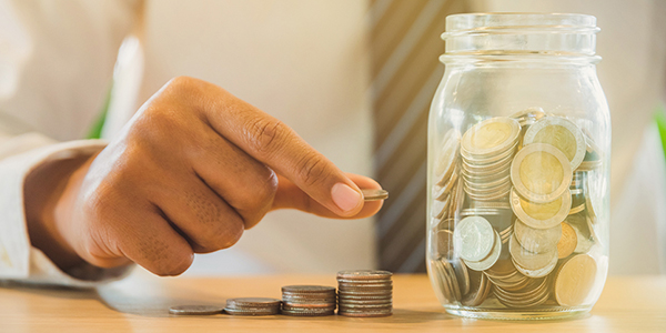 Businessman stacking coins into glass. Saving money concept